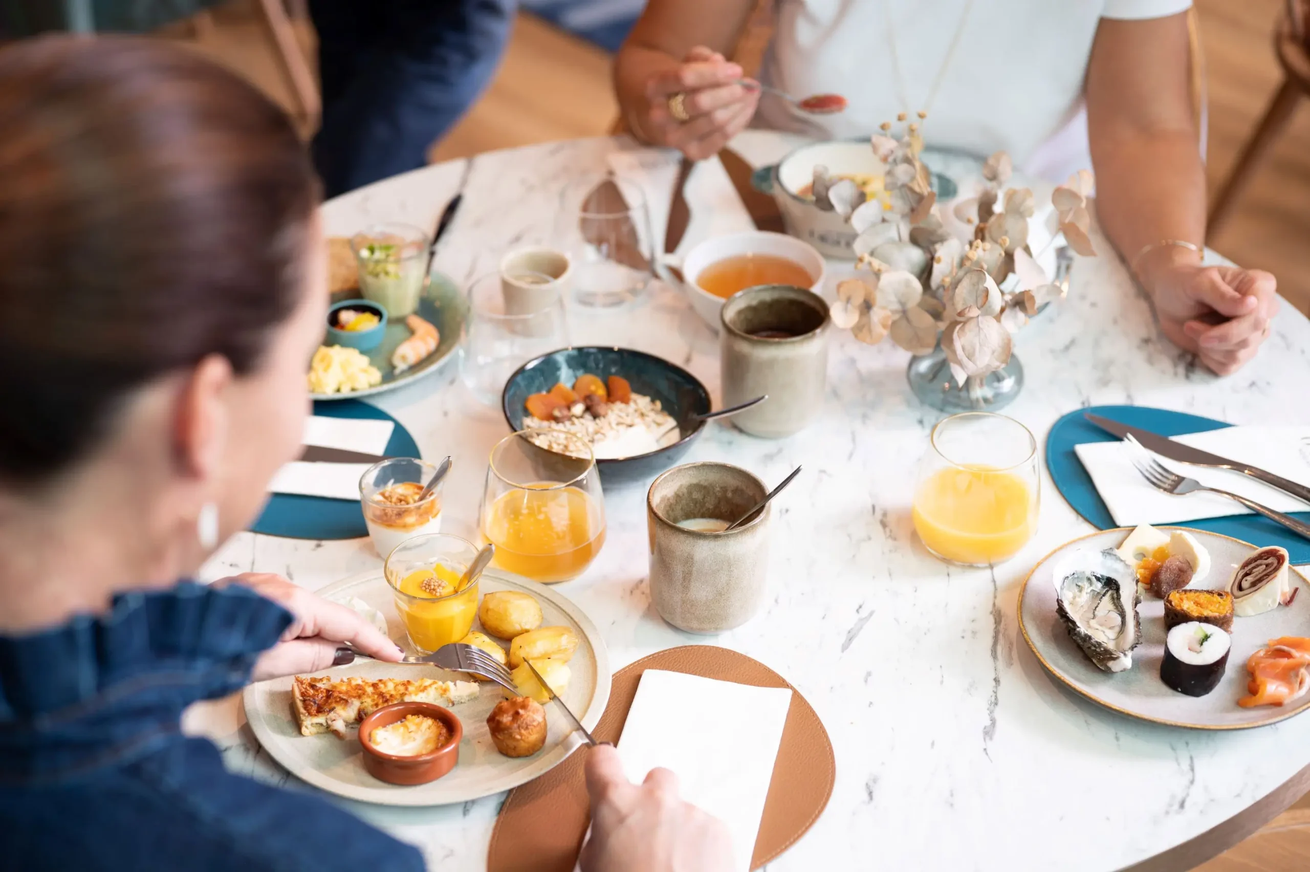 Convives autour d'une table de brunch en marbre avec huîtres, jus d'orange et produits locaux à la Maison OBONO