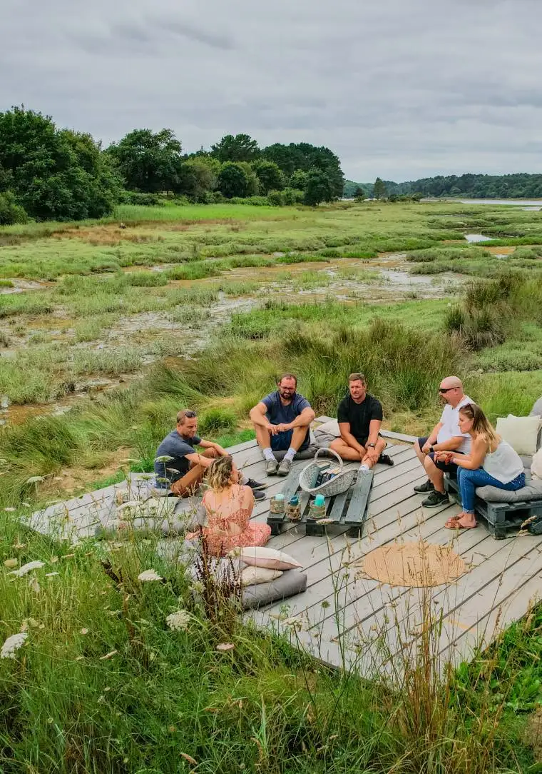 Groupe de collaborateurs en team building sur une terrasse en bois au cœur de la nature bretonne, près de la Maison OBONO
