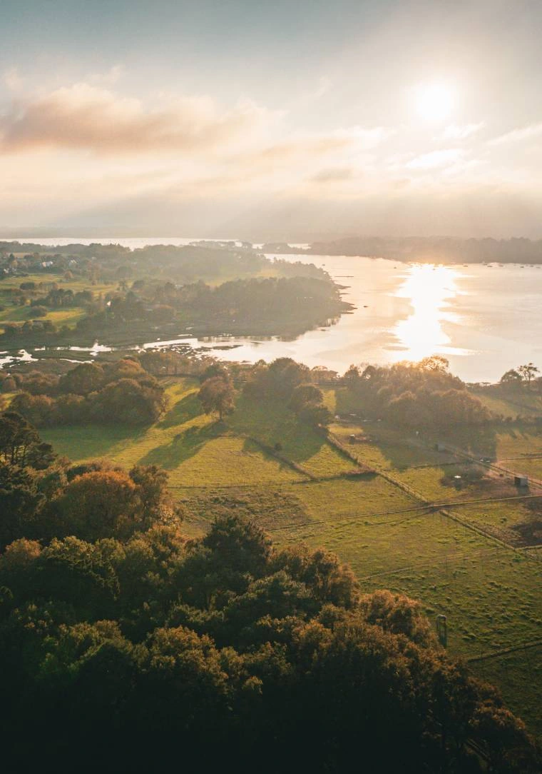 Vue aérienne du Golfe du Morbihan au coucher du soleil, prairies verdoyantes et rivière scintillante