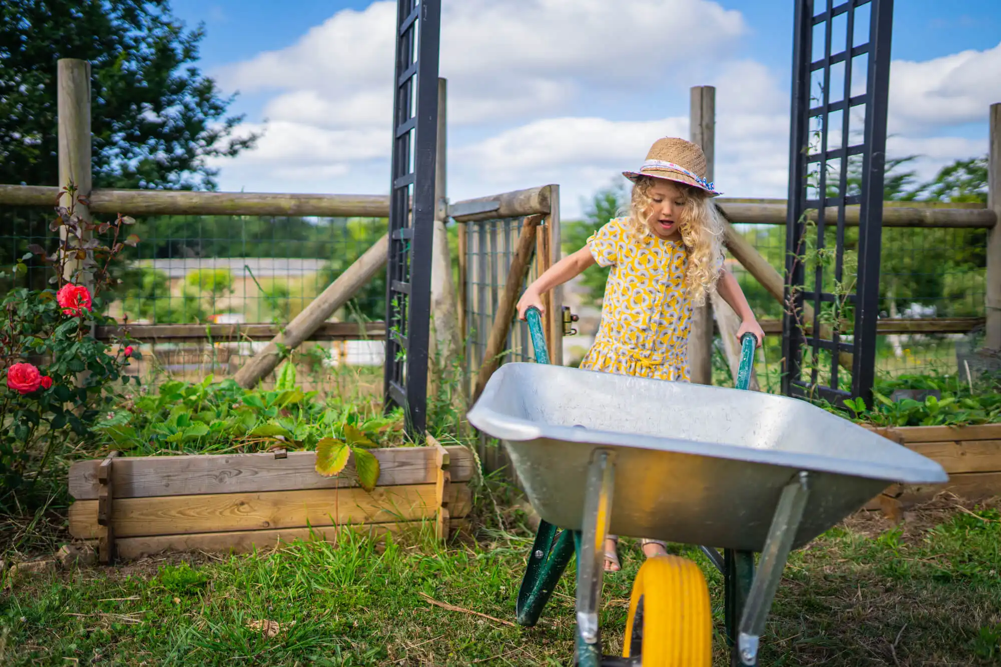 Enfant jouant avec une brouette dans le jardin potager de la Maison OBONO