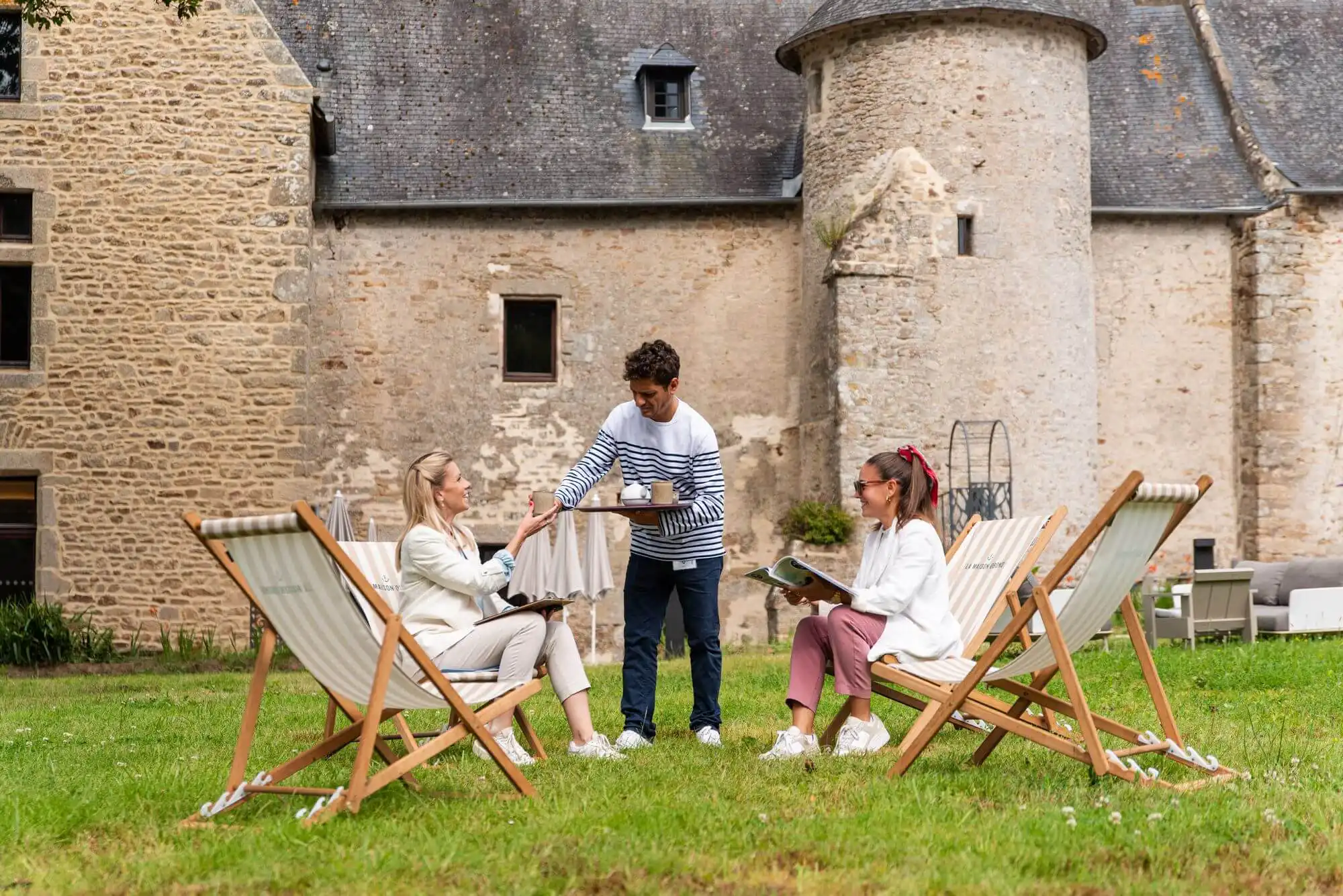 Serveur apportant des boissons à deux personnes installées sur la terrasse de la Maison OBONO